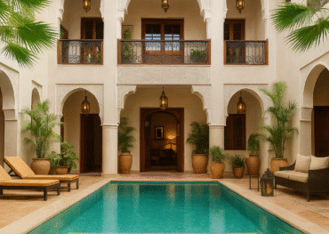 Patio interior de un riad de lujo en Marrakech con piscina central, palmeras, mosaicos tradicionales y lámparas árabes colgantes.