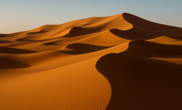 Dunas doradas del Sahara en Merzouga iluminadas por el sol al atardecer